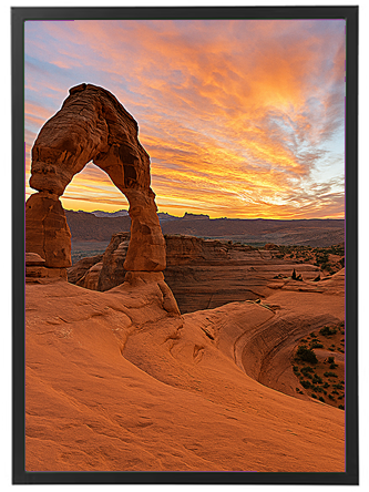 En betagende solnedgang bag Delicate Arch i Utah, med farverige skyer og sandstenslandskab.