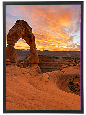 En betagende solnedgang bag Delicate Arch i Utah, med farverige skyer og sandstenslandskab.