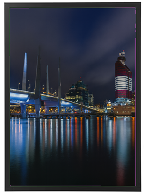 Et natbillede af en by med lysrefleksioner i vandet og moderne bygninger.