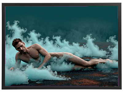 En nøgen mand ligger på jorden omgivet af farvet tåge, der skaber en drømmende stemning.