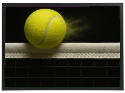 En gul tennisbold svæver over nettet, med støv der flyver fra bolden.