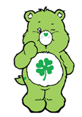 En sød, grøn bamse med et kløvermotiv på maven, der står med et smil.