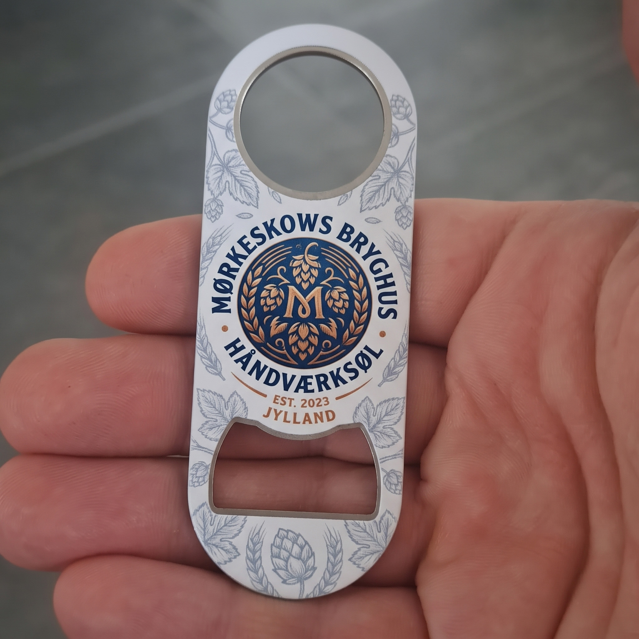 Design Selv Øloplukker i Hvid – Skræddersyet til UV-Print - Gør det lidt sjovere at knappe en kold forfriskning op med en helt personlig øloplukker! Denne flade og robuste flaskeåbner er designet med en glat, hvid overflade, der er specielt fremstillet til UV-print. Den hvide baggrund fungerer som det perfekte lærred, der sikrer, at dine farver, billeder, logoer eller sjove citater står knivskarpt og farvestrålende frem.

Oplukkeren har det klassiske og strømlinede "speed opener"-design, som kendes fra professionelle bartendere. Den ligger fantastisk i hånden, er lynhurtig at bruge, og det praktiske hul i toppen gør det nemt at hænge den op i hjemmebaren eller binde en lædersnor i.

Den er det oplagte valg til personlige gaver som f.eks. til Fars Dag, svendegaven eller til hjemmebaren. Samtidig er den helt perfekt som professionel merchandise for virksomheder, foreninger, festivaler eller mikrobryggerier, der ønsker deres logo i hænderne på deres kunder.

Specifikationer:

Materiale: Slidstærkt metal med hvid, printvenlig belægning

Design: Flad "speed opener" med hul til ophæng

Farve: Hvid (giver maksimal farvegengivelse ved print)

Trykmetode: Optimeret til UV-print på den store, flade overflade

Anvendelsesmuligheder: Personlige gaver, merchandise, firmagaver, festivaler og hjemmebarer