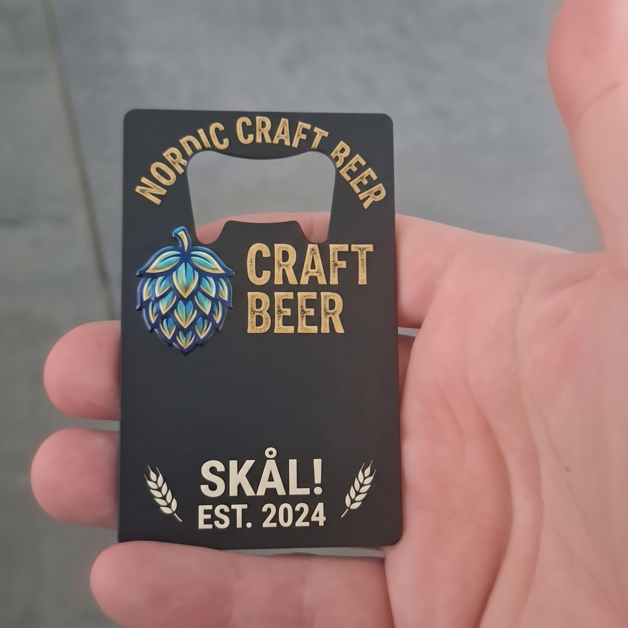 Design Selv Oplukker i Kreditkort-format (Sort Metal) - Den smarte flaskeåbner, der altid er lige ved hånden (og i pungen!).

Gør din markedsføring eller den personlige gave helt uforglemmelig med denne ultra-flade flaskeåbner. Den er genialt designet med præcis samme dimensioner som et standard kreditkort, hvilket betyder, at den glider ubesværet ned i pungen eller kortholderen – så er du altid klar til at knappe en kold forfriskning op.

Oplukkeren er fremstillet i et robust og solidt metal med en utrolig flot, mat sort belægning, der giver et råt og eksklusivt udtryk. Den store, flade overflade under selve oplukker-hullet fungerer som det ultimative lærred for dit UV-print. Hvad enten du printer med fuld farve eller skaber et stilrent design med hvid blæk, vil dit motiv stå i en fantastisk og iøjnefaldende kontrast til den mørke baggrund.

Det er et oplagt produkt, hvis du vil tilbyde dine kunder et "visitkort", der med garanti ikke bliver smidt ud, fedt merchandise til festivaler og events, eller sjove, personlige gaver til fars dag og polterabends. (Tip: Den sorte overflade er også ideel, hvis du tilbyder lasergravering).

Specifikationer:

Design: Minimalistisk kreditkort-format, der passer i alle punge.

Materiale: Slidstærkt metal med mat sort finish, der ikke bøjer.

Trykmetode: Kæmpe, plan overflade, der er skræddersyet til UV-print (og gravering).

Anvendelsesmuligheder: "Heavy-duty" visitkort, merchandise, smarte gadgets og personlige gaver.
