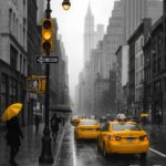 Gule taxaer kører på en regnvejrsdag i New York City med en person med en gul paraply.